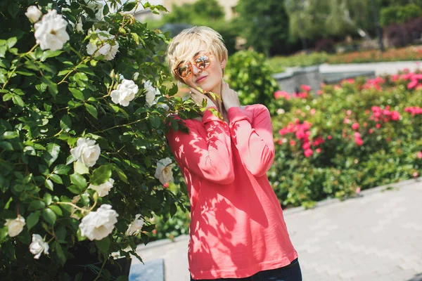 Parktaki güzel kız. Çiçek açan güller. Çeşme. — Stok fotoğraf