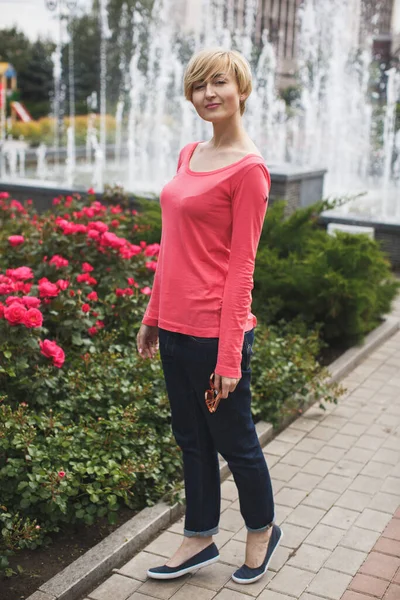 Vacker flicka i parken. Blommande rosor. Fontänen. — Stockfoto