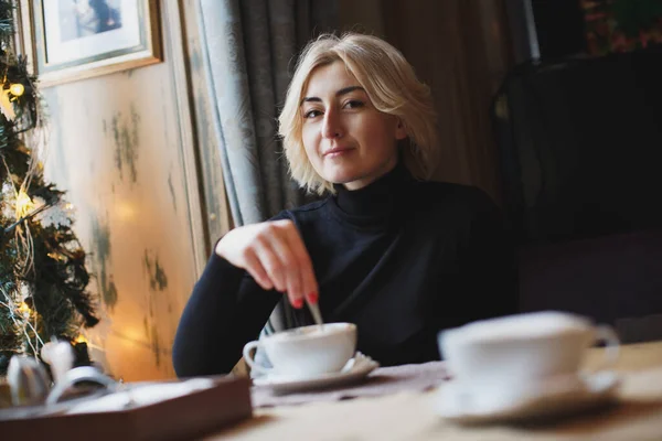 Una hermosa mujer bebe café de una taza blanca . — Foto de Stock