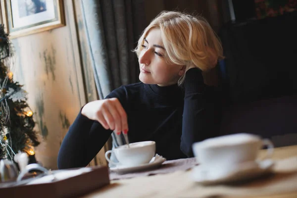 Una hermosa mujer bebe café de una taza blanca . — Foto de Stock