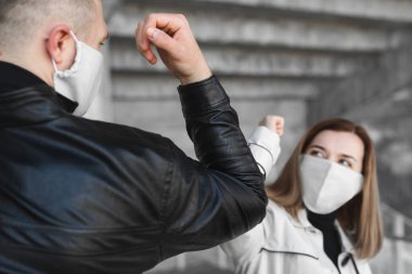 Dirsek çarpması. Koronavirüsün yayılmasını önlemek için yeni bir selamlama şekli, covid19. Erkek ve kadın sarılmak ya da tokalaşmak yerine dirseklerini birbirine vurur.