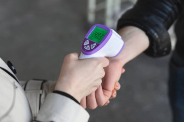 Coronavirus COVID-19 'un taranması ve korunması için dijital termometre ziyaretçisinin ateşini kontrol edin.