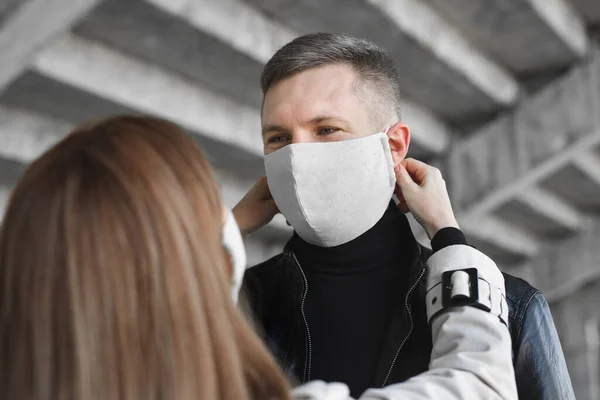 Una donna mette una maschera protettiva sul viso di un uomo. Coronavirus, merluzzo bianco19 — Foto Stock