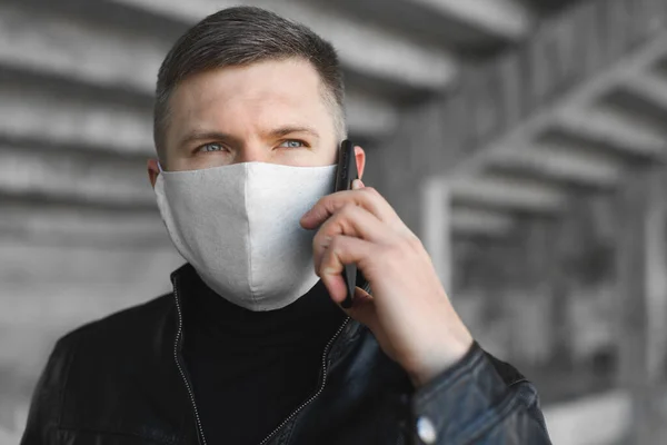 Giovanotto con una maschera medica e un telefono in mano per strada. Inquinamento atmosferico concetto di protezione coronavirus. Covid 19 — Foto Stock