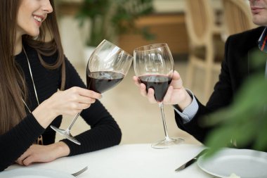 Erkek ve kadın kırmızı şarap içiyor. Resimde, gözlüklü yakın çekim eller..