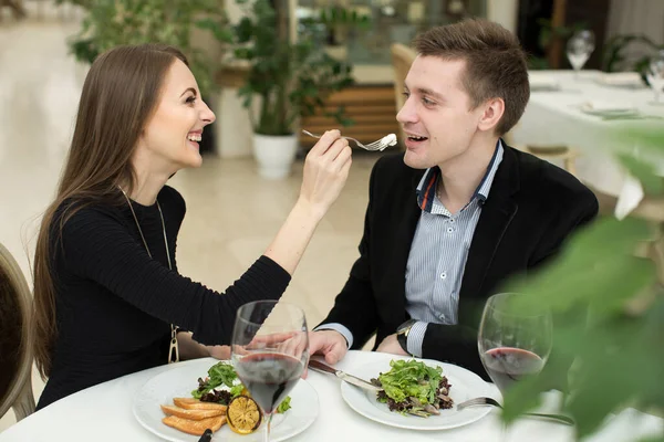 Красивая молодая пара кормит друг друга и улыбается, проводя время в ресторане . — стоковое фото