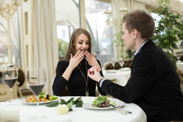 Man making marriage proposal to girlfriend at restaurant.