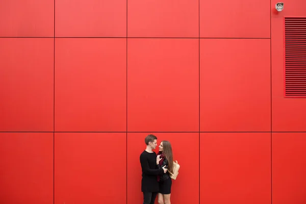 Jongeman en vrouw in passie, emotie, op straat met een achtergrond van de rode muur. Mode — Stockfoto