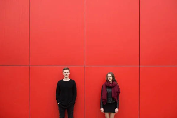 Young man and woman in passion, emotion, on the street with a backdrop of the red wall. Fashion — Stock Photo, Image