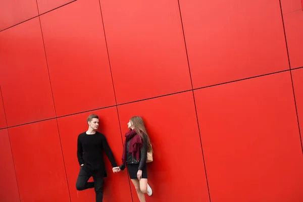 Молодой человек и женщина в страсти, эмоциях, на улице на фоне красной стены. Мода — стоковое фото