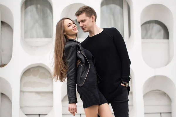 Jovem casal sexy em roupas pretas posando com um fundo na parede branca — Fotografia de Stock
