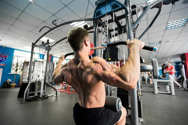 Omuz çekme makinesi. Jimnastik salonunda spor yapan fitness adamı. Üst sırt için üst vücut kuvveti egzersizi..