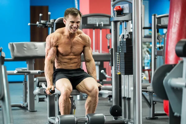 Atletische sterke bodybuilder uit te voeren oefening in sportzaal op de ongelijke bars. — Stockfoto