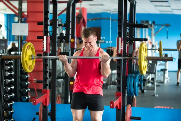 Fit man tillen zware lange halter in gewichten kamer in de sportschool. — Stockfoto