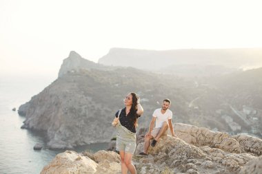 Aşıklar, erkek ve kız, uçurumun kenarında, dağların ve okyanusun arka planına karşı