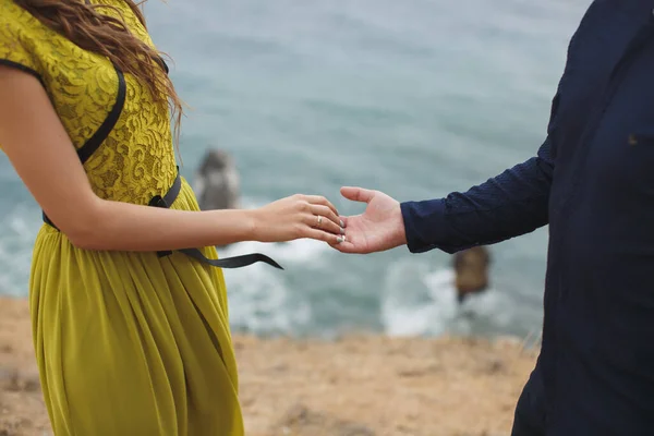Junge und Mädchen halten Händchen auf einer Klippe mit Blick auf das Meer. — Stockfoto