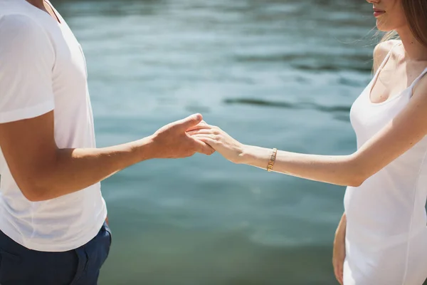 Junges Paar Junge und Mädchen weißes Kleid Händchen haltend auf dem Hintergrund des Wassers. — Stockfoto