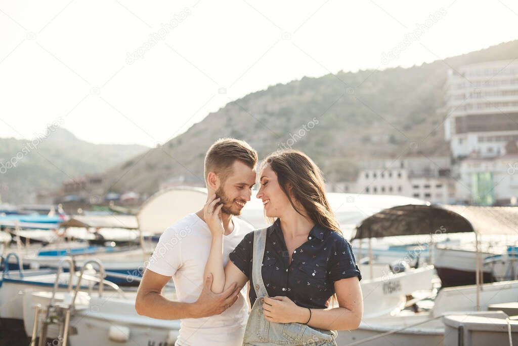 Lovers, boy and girl, walk on a wooden pier, hug and laugh