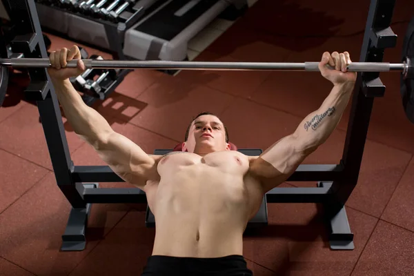Brutaler athletischer Mann pumpt beim Bankdrücken Muskeln auf. — Stockfoto
