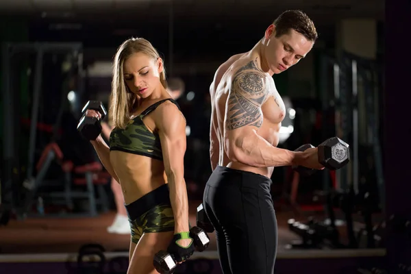 Gyönyörű fiatal sportos szexi pár mutatja izom és edzés a tornateremben. — Stock Fotó