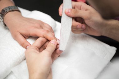 Erkek manikürcü kadınlar için güzellik salonunda manikür yapıyor.