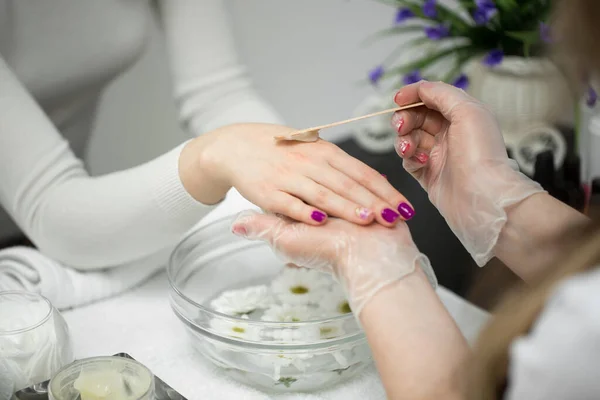 Mujer en un salón de uñas recibiendo una manicura, ella está bañando sus manos en parafina o cera —  Fotos de Stock