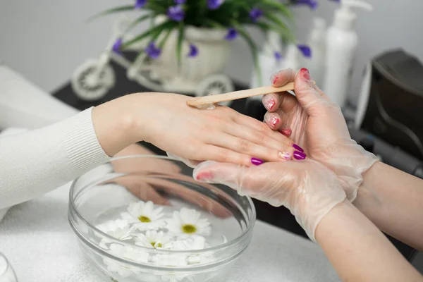 Woman in a nail salon receiving a manicure, she is bathing her hands in paraffin or wax — Stock Photo, Image