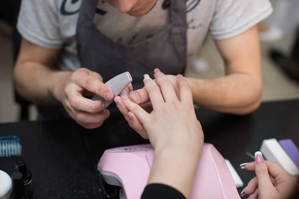 Closeup tiro homem fazendo manicure para mulher no salão de beleza . — Fotografia de Stock