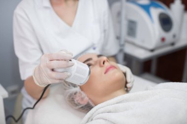 Kozmetoloji. Güzel kadın yüz derisi ultrason yarığı alıyor. Ultrason Cavitation Machine kullanarak Yaşlanma Karşıtı Kozmetik ürünleri alan Kadın Yüze Yakın Çekim. Vücut Bakımı.