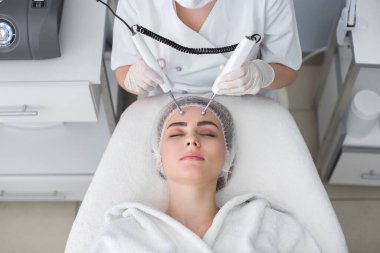 Makro, kaplıcada kozmetik galvanik güzellik tedavisi gören kadın portresi. Terapist, yüzüne elektrotlar takarak düşük frekanslı akım uyguluyor..