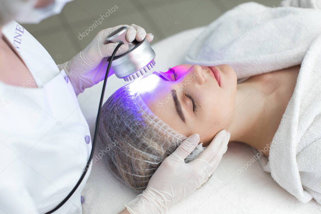 Ultrasonic massager. Light skin treatment, the woman in the beauty salon.