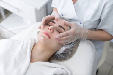 Doktor hastaların yüzüne masaj yapıyor. Model ve doktor. Kozmetik kliniği. Tıbbi ekipman. Sağlık, klinik, kozmetoloji.