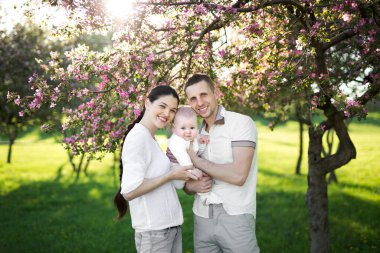 Çocuklu genç bir ailenin portresi. Mutlu bir genç aile yaz günü dışarıda vakit geçirir. Aile yaşamında mutluluk ve uyum. Mutlu aile kavramı