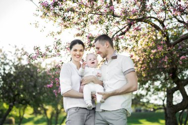 Çocuklu genç bir ailenin portresi. Mutlu bir genç aile yaz günü dışarıda vakit geçirir. Aile yaşamında mutluluk ve uyum. Mutlu aile kavramı