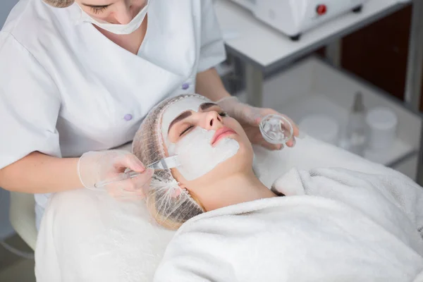 Maska do obierania twarzy, zabiegi pielęgnacyjne, pielęgnacja skóry. Kobieta otrzymuje pielęgnację twarzy od kosmetyczki w salonie spa. — Zdjęcie stockowe