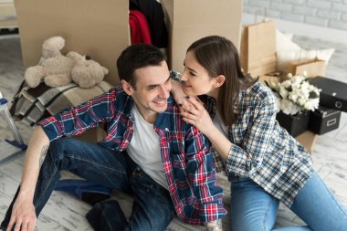 Yeni bir evde genç bir çift büyük kutuların arkasında dinleniyor. Yeni eve taşınma kavramı, birlikte yaşamaya başladık.