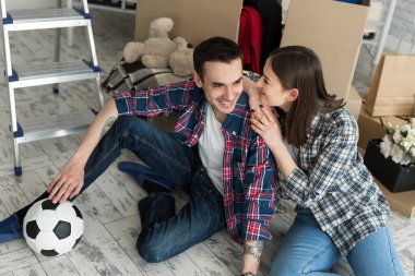 Yeni bir evde genç bir çift büyük kutuların arkasında dinleniyor. Yeni eve taşınma kavramı, birlikte yaşamaya başladık.