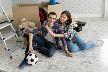 Yeni bir evde genç bir çift büyük kutuların arkasında dinleniyor. Yeni eve taşınma kavramı, birlikte yaşamaya başladık.