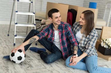 Yeni bir evde genç bir çift büyük kutuların arkasında dinleniyor. Yeni eve taşınma kavramı, birlikte yaşamaya başladık.