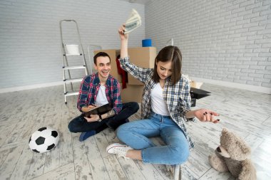 Genç çift yeni dairede yerde otururken para sayıyor..