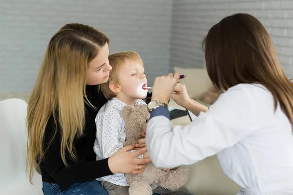 Ärzte untersuchen die Kehle der Kinder. Junge und Mutter in Kinderarztpraxis — Stockfoto