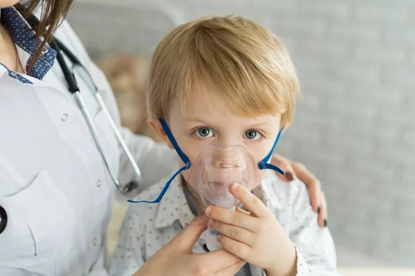 의사가 흡입기 의가 면으로 천식 흡입 요법을 사용하는 어린아이에게 약물 흡입 치료를 실시하고 있다 — 스톡 사진