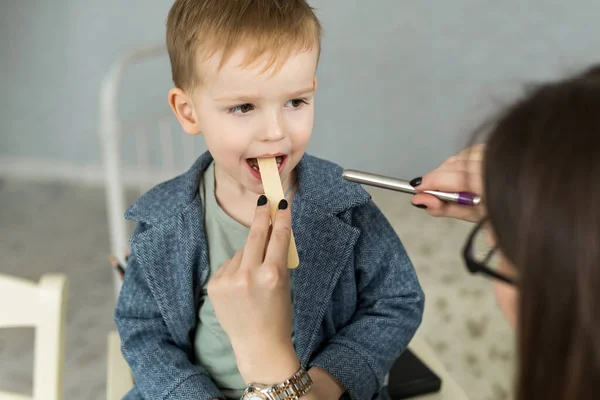 Doktor çocuğun boğazını muayene ediyor. Çocuk doktoru muayenehanesindeki çocuk.
