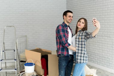 Genç çift yeni bir daireye taşınırken selfie çekiyor. Yeni evliler için yeni bir ev