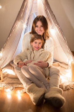 Güzel bir anne ve kız, Noel arifesi, rahat bir yerde oturuyor. Yeni Yıl