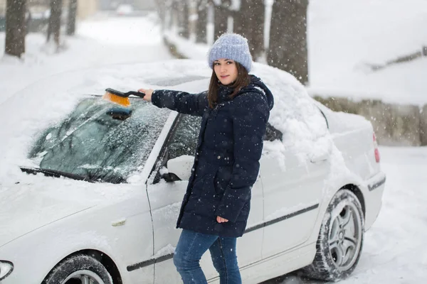 Mulher bonita removendo neve do pára-brisas do carro . — Fotografia de Stock