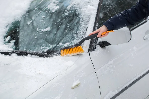 Beautiful woman removing snow from car windshield. — Stock Photo, Image