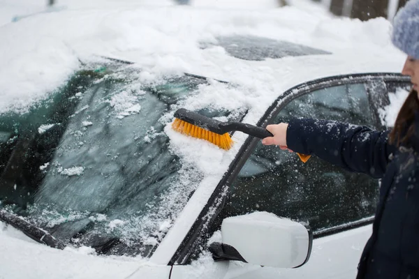 Mulher bonita removendo neve do pára-brisas do carro . — Fotografia de Stock