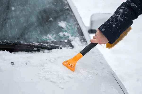 Mulher limpando neve do carro no inverno . — Fotografia de Stock