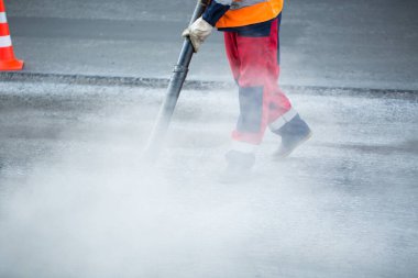 Tramvay pisti yenileme çalışmaları sırasında daha iyi asfalt yapışması için tozu temizleyen yaprak üfleyici işçisi..